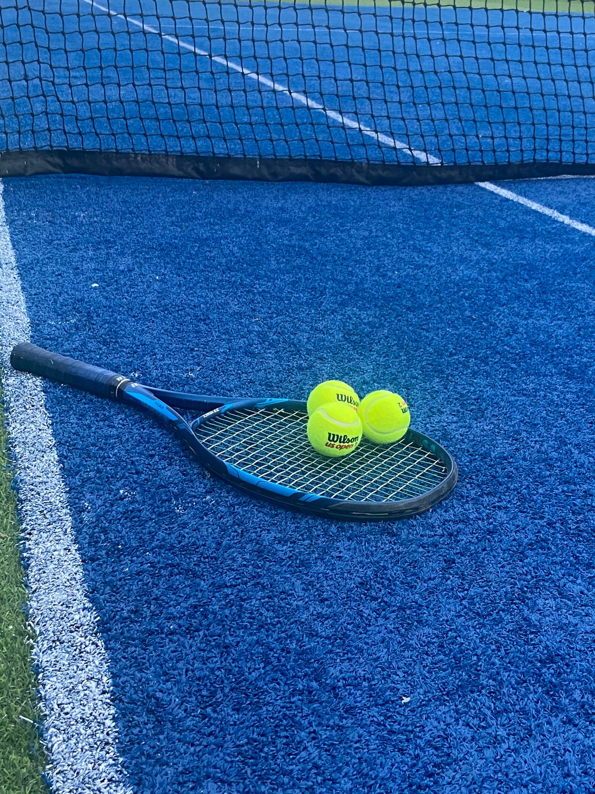 Tennis equipment resting on a blue hard court surface